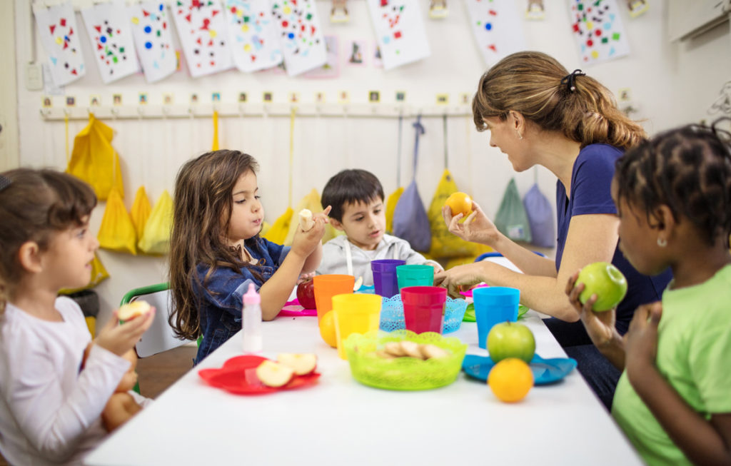 Children in day care at a table with day care worker