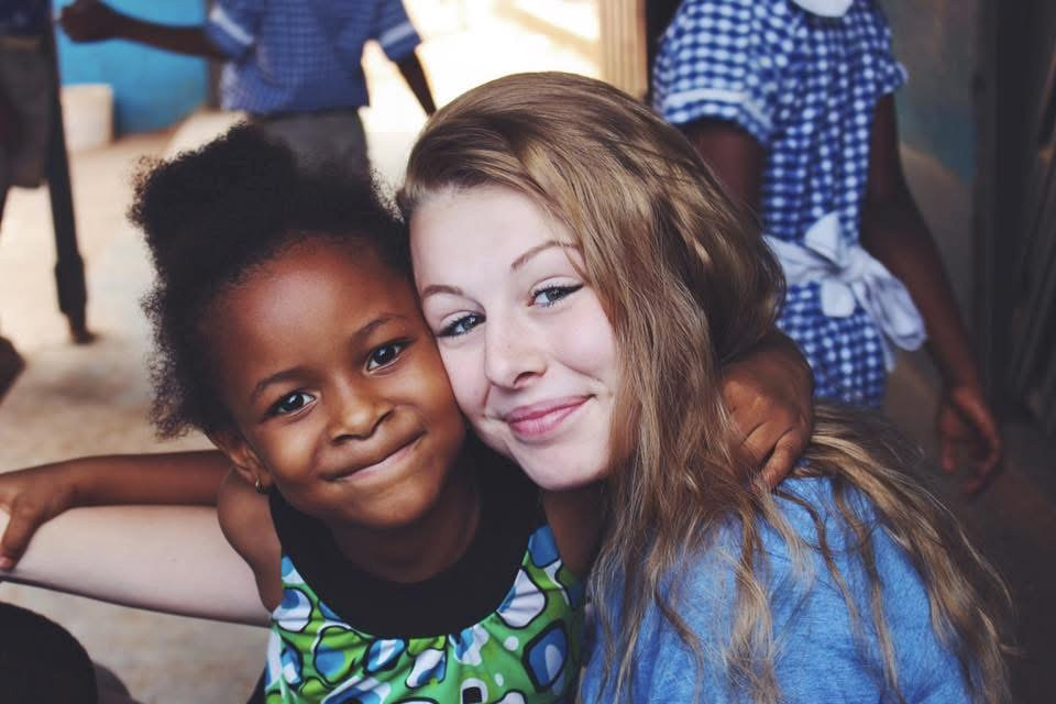 student posing with a child while on school service trip