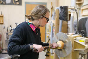 A woman turning a bowl on a lathe.